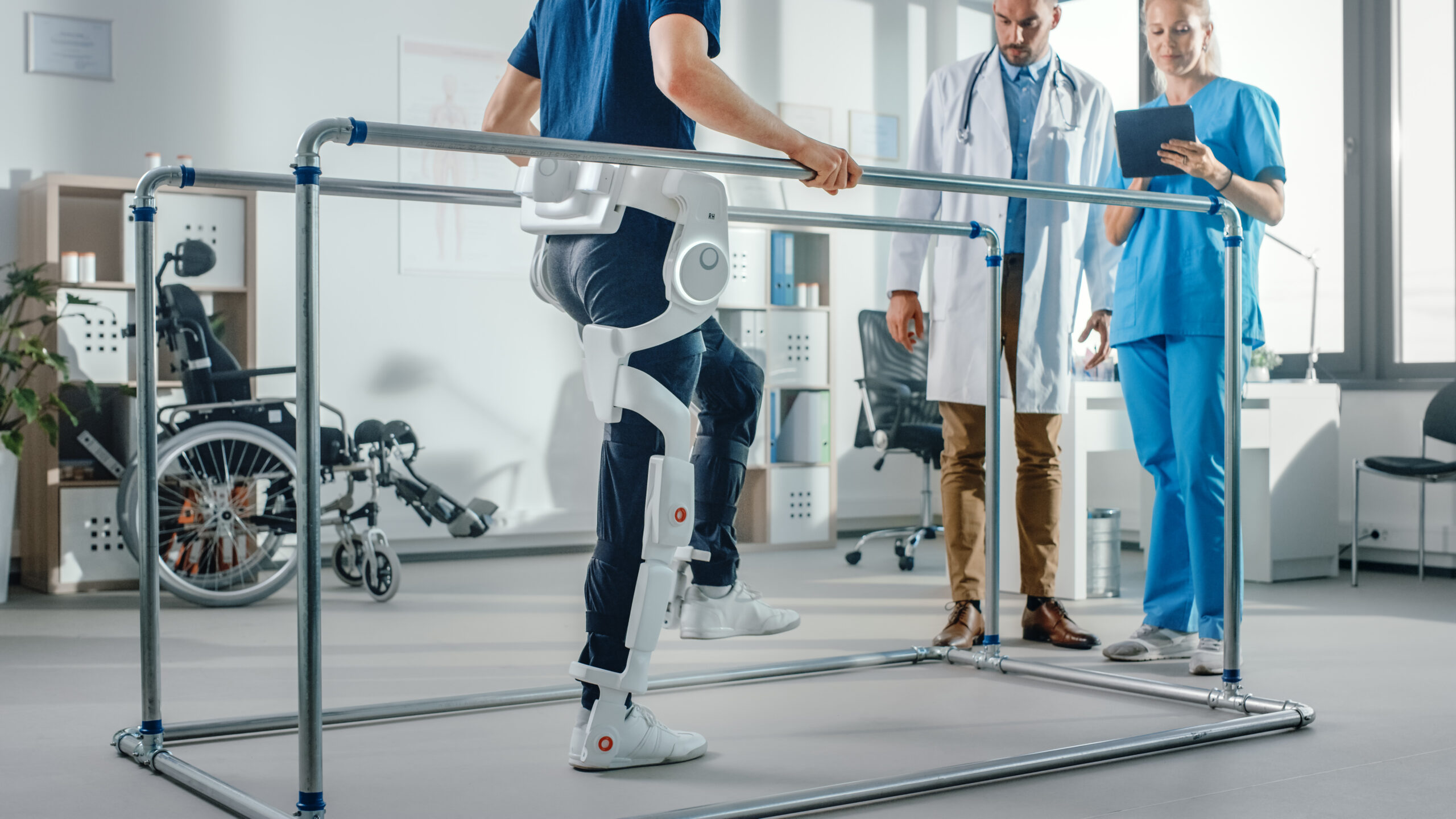 Patient in a robotic exoskeleton for leg mobility with healthcare professionals during rehabilitation.